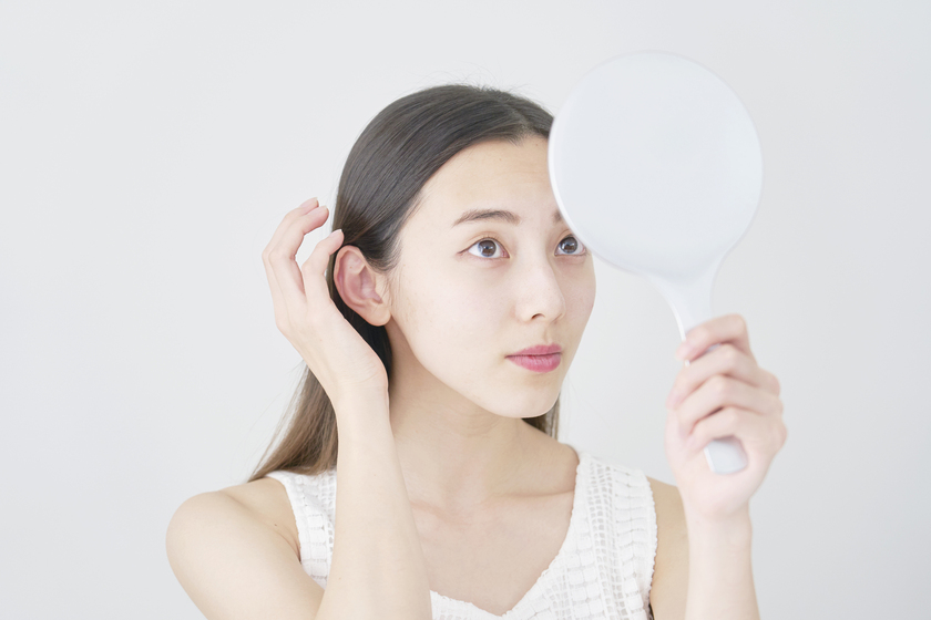 鏡で自分の髪を見る女性