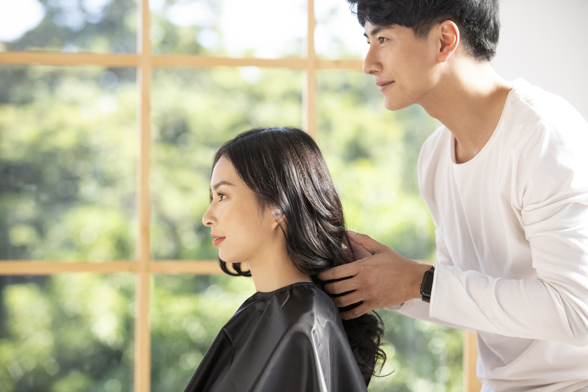 美容師が女性の髪を触る画像