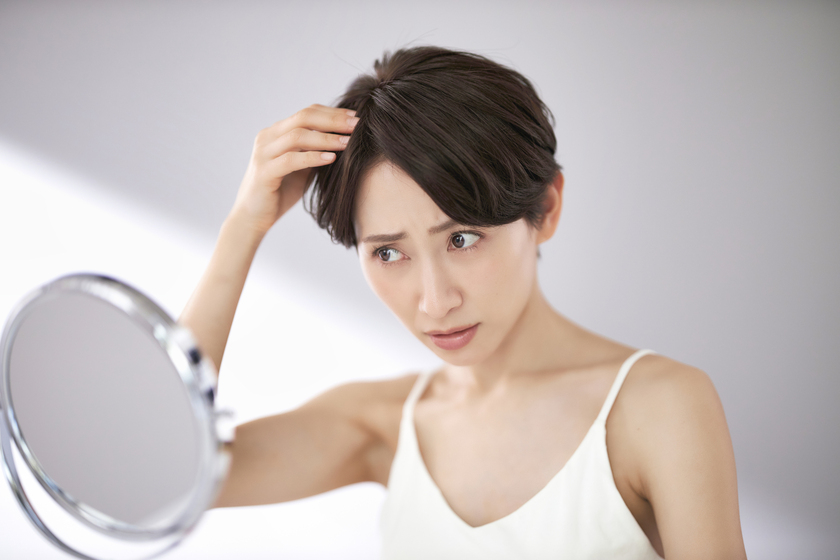 鏡で髪の分け目を見る画像